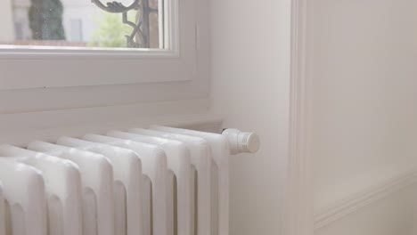 Woman-turning-down-heating-adjusting-radiator