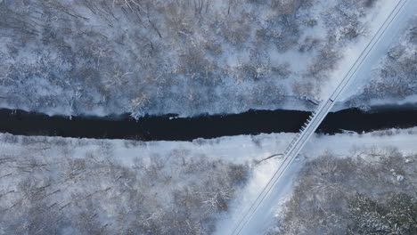 Winter-Bridge-Crossing-Over-Partially-Frozen-River,-Aerial-Top-Down