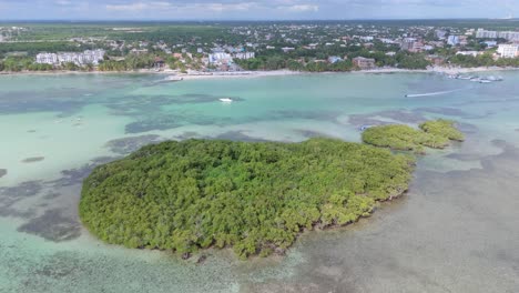 Drohnenaufnahme-Zeigt-Tropische-Insel,-Jetski,-Sandstrand-Von-Boca-Chica-Und-Die-Stadt-Santo-Domingo-Im-Hintergrund