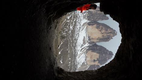 Video-Vertical-De-Tre-Cime-Di-Lavaredo-Visto-A-Través-De-Una-Cueva,-Aparece-Una-Mujer-Excursionista