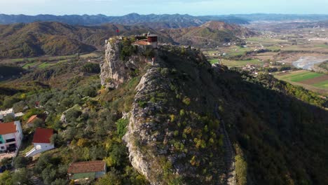 Guardian-of-the-Peaks:-Aerial-View-of-Ancient-Fortress-Perched-on-Rocky-Heights,-Overlooking-Majestic-Mountains-and-Hills-in-Albania