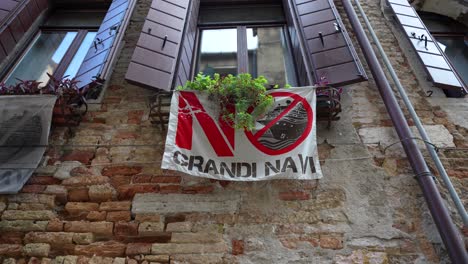 Window-with-No-Big-Cruises-flag-on-old-brick-house-in-Venice,-view-from-bellow