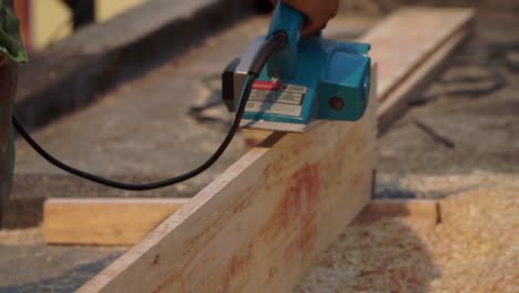 Carpenter-hand-work-using-planer-machine-to-smooth-the-surface-of-plank-wood