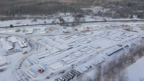 Aerial,-Snow-Covered-Construction-Supply-Yard-during-Winter