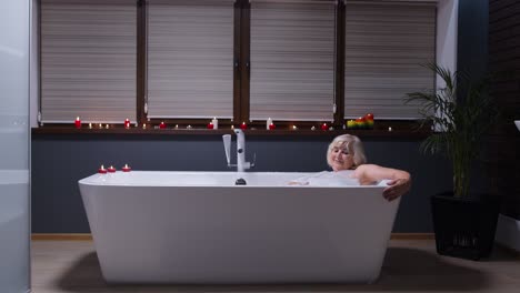 Beautiful-active-senior-woman-lying-in-warm-bath-with-bubbles,-enjoying-relaxation.-Elderly-people