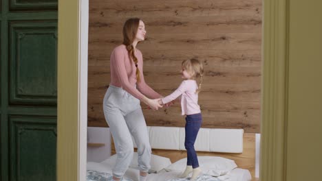 Happy-funny-family-mother-and-child-kid-daughter-dancing,-jumping-on-bed,-listening-music-at-home
