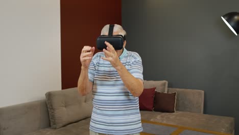 Happy-senior-man-using-virtual-reality-headset-glasses,-trying-to-touch-something,-watching-3D-video