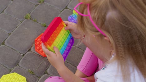Kind-Mädchen-Spielen-Bunte-Matschige-Silikonblasen-Sensorisches-Spielzeug-Einfaches-Dimple-Pop-It-Spiel,-Nahaufnahme