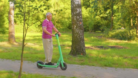 Abuelo-Hombre-Mayor-Y-Elegante-Montando-Scooter-Eléctrico-En-El-Parque,-Abuelo-Moderno-Conduciendo-Vehículo-Urbano