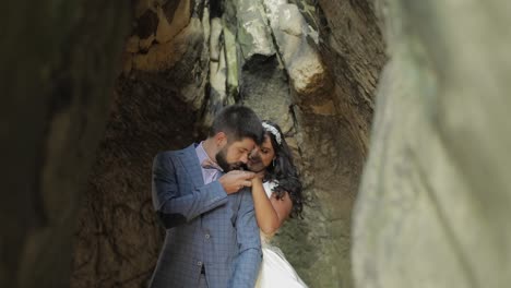 Groom-with-bride-standing-in-cave-of-mountain-hills.-Wedding-couple-in-love
