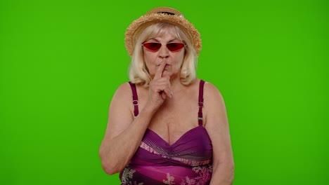 Elderly-woman-tourist-holding-finger-near-lips-for-silence-sign,-hush,-secret,-silence-on-chroma-key