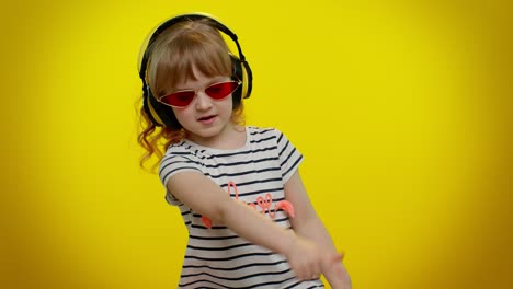 Cheerful-cute-blonde-child-kid-listening-music-via-headphones-dancing-disco-fooling-having-fun-party