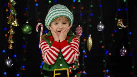 Excited-kid-girl-in-Christmas-elf-Santa-Claus-helper-costume.-Child-doing-winner-gesture,-say-Yes