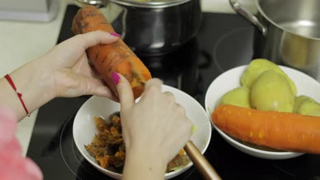 Female-housewife-hands-peeling-carrot-in-the-kitchen.