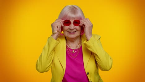 Happy-playful-elderly-granny-woman-in-red-sunglasses-blinking-eye,-looking-at-camera-with-smile