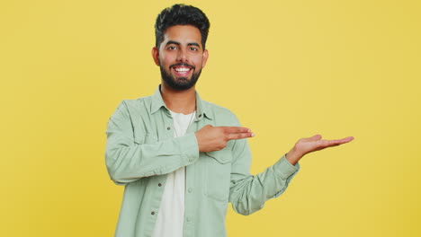 Young-man-showing-thumbs-up-and-pointing-at-right-on-blank-space-place-for-your-advertisement-logo