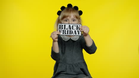 Child-girl-showing-Black-Friday-inscription,-smiling,-looking-satisfied-with-low-prices,-discounts