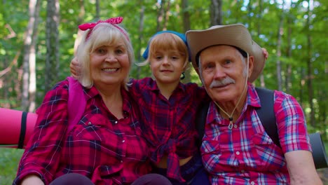 Active-senior-grandmother-grandfather-tourists-sitting,-hiking-with-granddaughter-in-summer-wood
