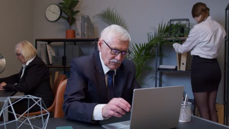 Gelangweilter-älterer-Chef-Macht-Gesichtspalm-Geste,-Während-Er-Ein-Neues-Projekt-Auf-Dem-Laptop-Computer-Entwickelt