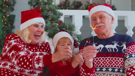 Glückliches-älteres-Großelternpaar-Mit-Enkelin,-Die-Brennende-Bengalische-Weihnachtslichter-In-Der-Hand-Hält