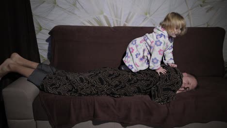 Little-girl-in-bathrobe-waking-her-father-up.-Man-sleeps-on-the-couch