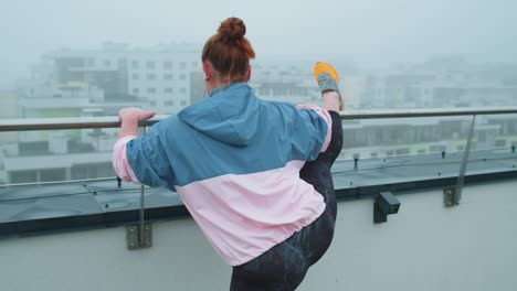 Sportlich-Fitte-Frau-In-Blau-rosa-Sportbekleidung-Macht-Kniebeugen-Yoga-Stretching-Übungen-Auf-Dem-Dach-Des-Hauses