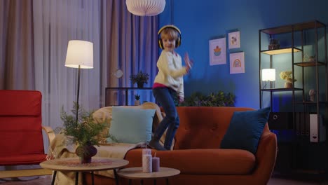 Happy-one-child-girl-kid-in-headphones-dancing-trendy-dance-while-listening-to-music-at-home-alone