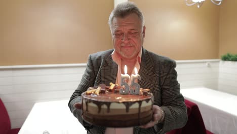 Happy-respectable-old-man-holding-cake.-Celebrating.-Blowing-birthday-candles