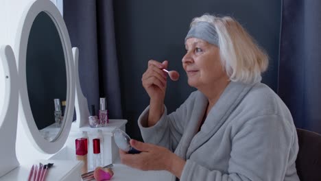 Old-senior-woman-grandmother-taking-care-of-skin,-applying-anti-wrinkle-foundation-powder-with-brush