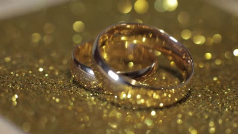 Wedding-gols-rings-lying-on-shiny-glossy-surface.-Shining-with-light.-Close-up