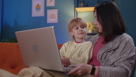 Mutter-Und-Kleine-Tochter-Lernen-Am-Laptop,-Schauen-Lustige-Filme,-Entspannen-Sich,-Liegen-Auf-Dem-Sofa