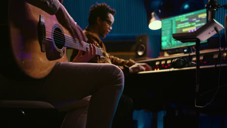 Creative-musician-singing-guitar-in-professional-studio-control-room