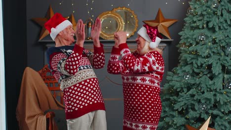 Cheerful-married-senior-couple-grandparents-celebrating-success-win-scream-rejoices-on-Christmas