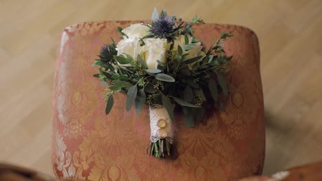 Wedding-rings-lie-on-a-beautiful-wedding-bouquet-which-lays-on-the-chair