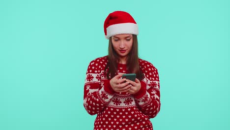 Erwachsenes-Teenager-Mädchen-Im-Weihnachtspullover-Schaut-Auf-Smartphone-Display-Und-Freut-Sich-Aufrichtig-über-Erfolg-Und-Glück