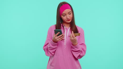 Teen-girl-using-credit-bank-card-and-smartphone-while-transferring-money,-purchases-online-shopping