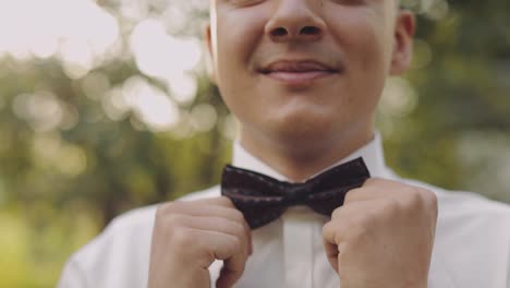 Handsome-groom-fixes-his-bow-tie.-Close-up-shot.-Wedding-morning.