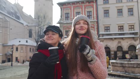 Zwei-Lächelnde-Touristinnen,-Die-Zusammen-Reisen-Und-Heißen-Tee-Und-Kaffee-Aus-Tassen-Auf-Der-Stadtstraße-Trinken