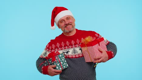 Cheerful-man-in-Santa-sweater-presenting-two-Christmas-gift-boxes,-stretches-out-his-hands-to-camera