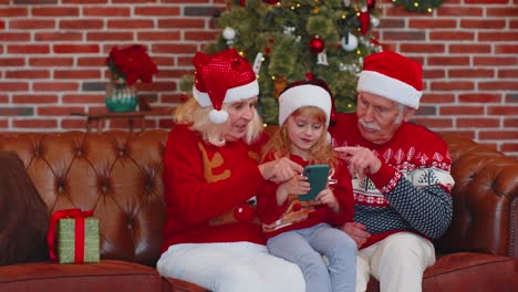 Großeltern-Und-Enkelin-Aus-Der-älteren-Familie-Kaufen-Weihnachtsgeschenke-Online-Per-Handy,-Shoppen