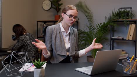 Focused-businesswoman-waving-hand-hi-hello-bye,-talking,-looking-into-laptop-computer-at-home-office