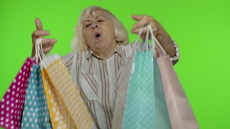 Senior-grandmother-raising-shopping-bags,-celebrating,-satisfied-with-purchase,-discount.-Chroma-key