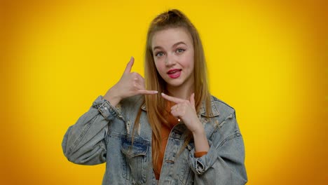 Teenager-girl-in-denim-jacket-looking-at-camera-doing-phone-gesture-like-says-hey-you-call-me-back