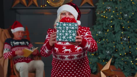 Reife-Großmutter-Im-Neujahrspullover-Und--hut-Präsentiert-Weihnachtsgeschenkbox,-Feiertage-Zu-Hause