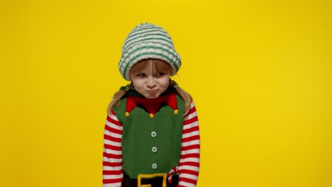 Displesed-kid-girl-in-Christmas-elf-Santa-helper-costume-keeps-thumb-down-and-shows-dislike-gesture