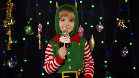 Kind-Mädchen-In-Weihnachten-Elf-Santa-Claus-Helfer-Kostüm-Lecken-Süßigkeiten-Lutscher-Karamell-Süßigkeiten