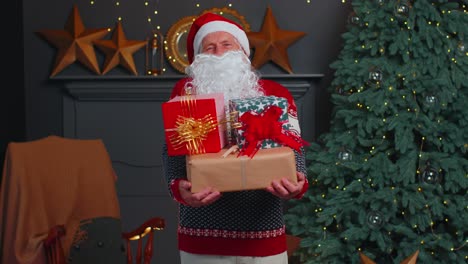 Senior-grandfather-parodies-Santa-Claus-presenting-Christmas-gift-box,-holidays-celebration-at-home