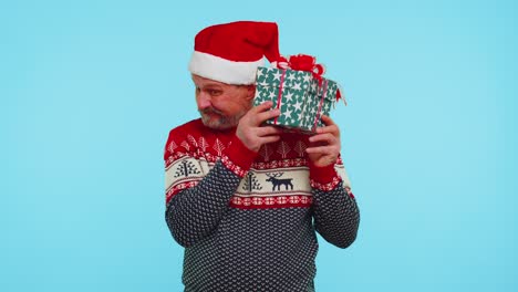 Funny-man-wears-Christmas-sweater-with-deers-received-present,-interested-in-what-inside-gift-box