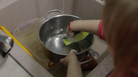 Child-washing-dishes-in-the-kitchen.-Close-up-of-girls-hands