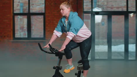 Mujer-Atlética-Montando-Una-Rutina-De-Entrenamiento-En-Bicicleta-Estacionaria-Giratoria-En-Un-Gimnasio-De-Niebla,-Pérdida-De-Peso-En-Interiores